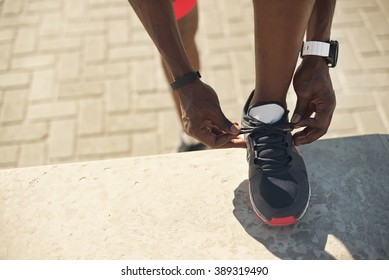 A Closeup Shot Of A Young Black Man Tying His Sports Shoes Before A Workout.