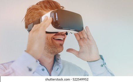 Closeup shot of young businessman using the virtual reality headset and smiling. Male executive wearing VR goggles. - Powered by Shutterstock