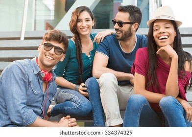 Closeup Shot Of Young Friends Sitting On Staircase Having Fun. Happy Girls And Guys Smiling And Looking At Camera. Young Men And Young Women Stay Together.