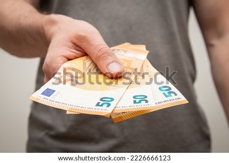 A closeup shot of a young man holding 150 euros in his hand