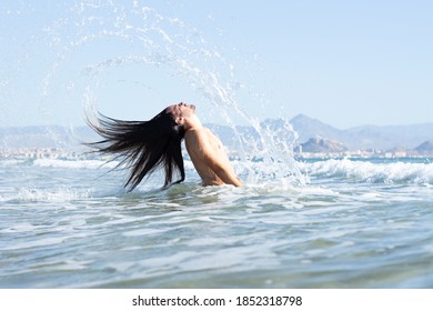 A Closeup Shot Of A Young Man With Long Hair Doing A Hair Flip In The Water