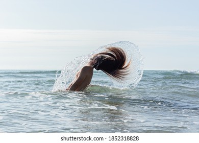 A Closeup Shot Of A Young Man With Long Hair Doing A Hair Flip In The Water