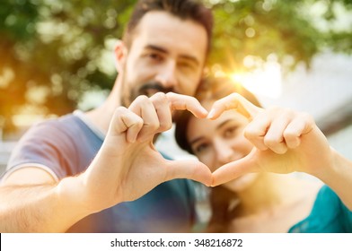 Closeup Shot Of Young Man And Woman Making Heart Shape With Hand. Loving Couple Making Heart Shape With Hands Outdoor. Female And Male Hands Making Up Heart Shape.