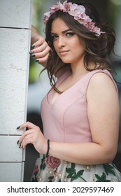 A Closeup Shot Of A Young Woman Posing Near A Building Wall In A Pink Dress And Flower Hairband