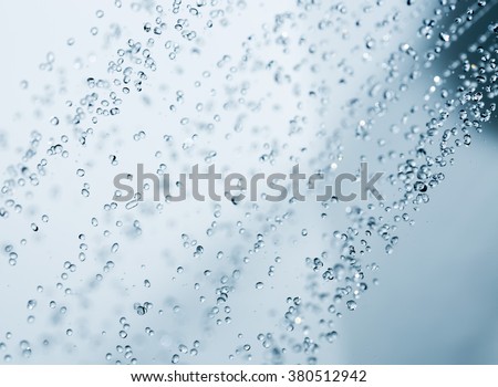 Closeup of a shower head with sprinkling water, blue toned photo.
