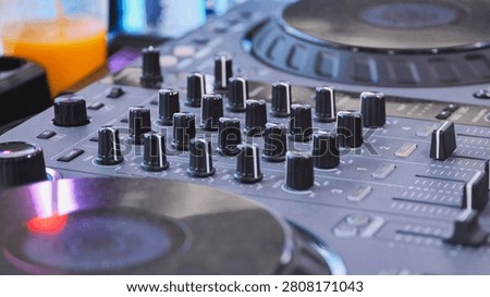Close-up showing a DJ controller with many knobs, faders, and buttons for mixing sound