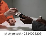 Close-up showing hands of individuals exchanging cigarette pack in formal business setting at table with reflections. The cigarette pack is being visibly handed over