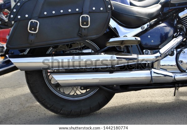 Close-up\
shows the rear of the motorcycle. Two exhaust pipes, rear wheel,\
passenger seat, black bag, engine, passenger footboard, spring for\
shock absorption, rear muffler and\
muffler.