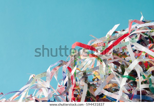 Closeup\
shredded paper texture and reuse colorful paper scrap of document\
on blue paper background. Selective focus\
image.