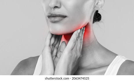 Closeup Of Sick Lady Having Sore Throat, Touching Her Neck With Red Inflamed Zone, Suffering From Laryngeal Disorder, Tonsillitis, Throat Cancer, Cold, Black And White Gray Studio Background, Banner