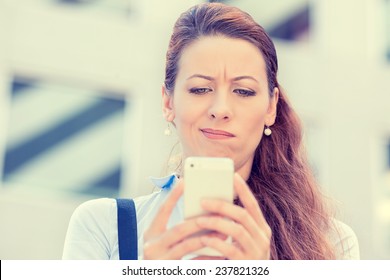 Closeup side profile portrait upset sad skeptical unhappy serious woman talking texting on phone displeased with conversation isolated city background. Negative human emotion face expression feeling