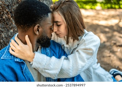 Close-up side top view of a romantic multiracial couple embraced sitting on a park - Powered by Shutterstock