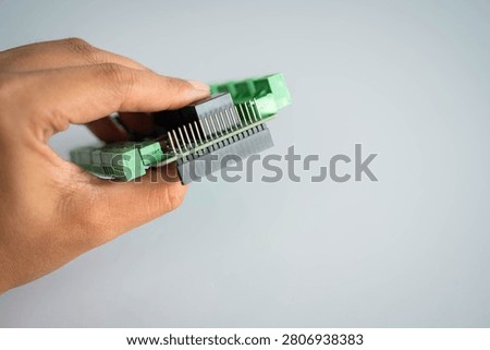 Close-up side view of an embedded controller board held by hand, highlighting pin headers and electronic connectors for IoT hardware, embedded systems, PCB engineering, electronics prototyping and industrial automation.