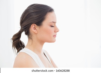 Close-up Side View Of A Fit Young Woman With Eyes Closed Against White Background