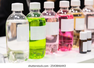 Close-up side view of group of plastic bottles with multi coloured beverages and white blank labels. Soft focus. Copy space. Drinks industry theme. - Powered by Shutterstock