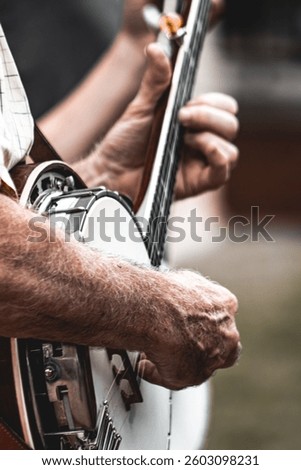 A closeup side view of man's hands playing banjo.