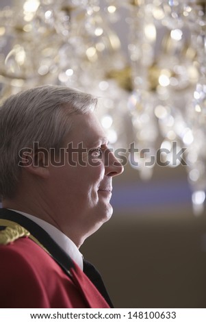 Closeup side view of middle aged porter in red jacket looking away