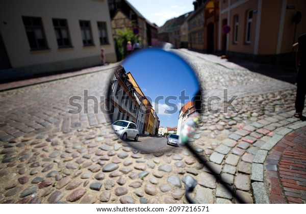 A closeup of the side view mirror reflecting the road\
with cars 
