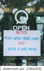 Close-up Of A Sign Adhered On A Small Business Commercial Storefront Door Letting Customers Know In English That Wash Hand And Protective Face Mask Is Required For Entry.