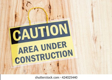 closeup the sign Caution area under construction on wood background