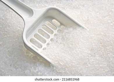 Close-up of silica gel filler and scoop in a cat litter box.