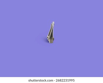 A close-up of a silver, cone-shaped object on a solid purple background with a soft shadow.
