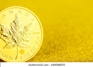 closeup of silver and golden canadian maple leaf one ounce coins on golden background placed on left side