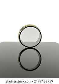 a close-up of a silver ring with a white background. ring is made of silver and has a shiny finish. ring is sitting on a black glass surface which is reflecting the ring.