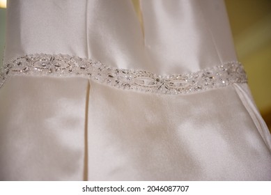 A Closeup Of A Simple Wedding Dress With Ornaments Under The Lights