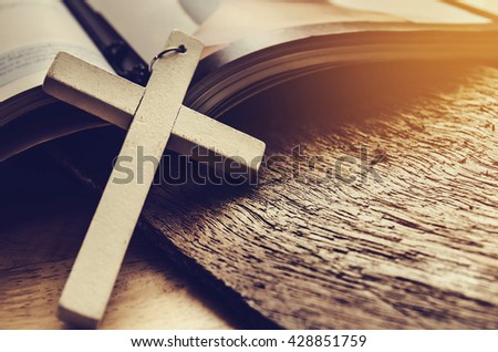 Closeup of simple wooden Christian cross necklace on  Bible , vintage tone , god