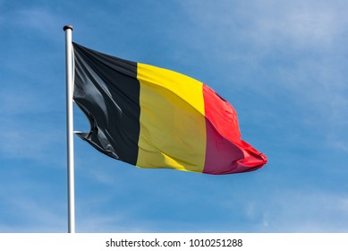 Closeup of single belgian flag waggling in the wind in front of blue sky