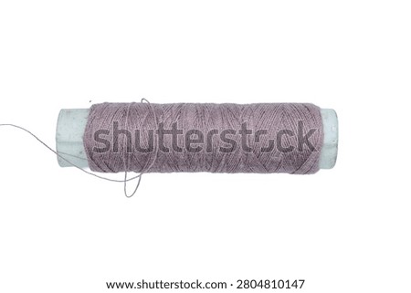 Close-up of a single spool of pinkish-brown thread on a white background, suitable for sewing, crafting, and textile-related projects, demonstrating color and texture
