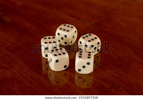 Closeup in six dices in wooden table with\
reflection. Brazilian game aka\
Bozó.