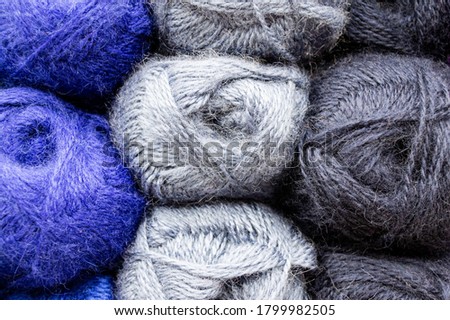 Close-up of skeins of thread in blue, light and dark grey colors. Thread background
