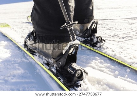 Close-up of skier getting his boot untight. Close-up of ski pole unfasten boot from ski.
