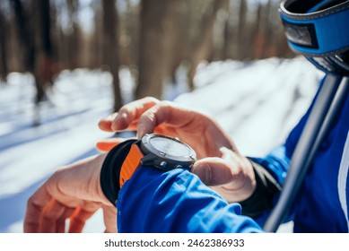 Close-up of a skier's hand adjusting a smartwatch in the snowy woods, a tool for monitoring time and performance during winter sports activities - Powered by Shutterstock