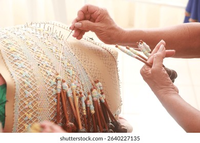 Close-up of a skilled artisan making bobbin lace with colorful threads on a lace pillow, showcasing traditional handmade craftsmanship. Renda de bilro. Aquiráz. Ceará.