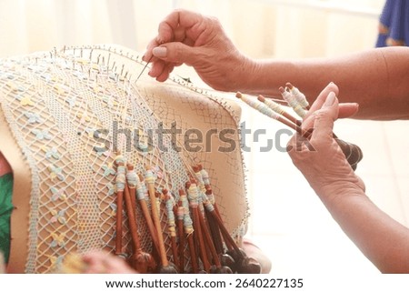 Close-up of a skilled artisan making bobbin lace with colorful threads on a lace pillow, showcasing traditional handmade craftsmanship. Renda de bilro. Aquiráz. Ceará.