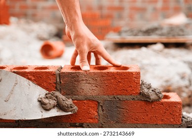Close-up of Skilled bricklayer laying bricks with trowel on construction site