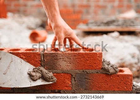 Close-up of Skilled bricklayer laying bricks with trowel on construction site