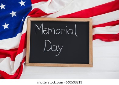 Close-up of slate with text and an American flag on wooden table - Shutterstock ID 660538213