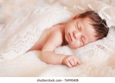 Closeup Of Sleeping Baby Lying On White Blanket With Hands In A Comfortable Position