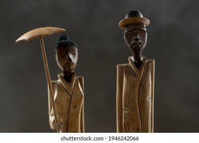Closeup of slender Cuban figurine souvenirs with a woman holding an umbrella and a man with cigar. Studio travel memorabilia low key object still life.