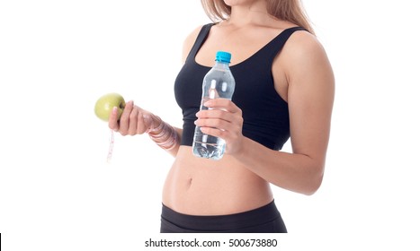 Close-up Of A Slender Girl Turned Sideways And Holding An Apple In One Hand And The Other Holding A Bottle Of Water