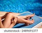 Close-up of slender legs by the pool, hand smearing protective cream before sunbathing to protect skin and prevent cancer.