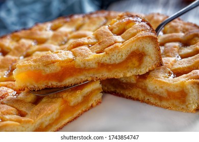 close-up of slice of apricot shortcrust pie with a lattice pie crust topping on a vintage cake shovel on a rustic wooden table, landscape view - Shutterstock ID 1743854747