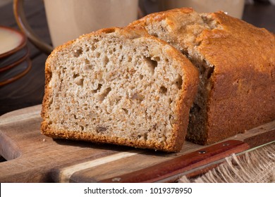 Closeup Of A Slice Of Banana Nut Bread On A Wooden Cutting Board