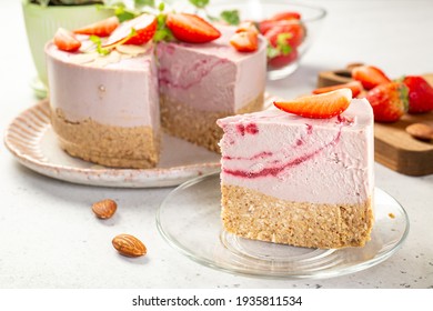 Close-up of  slice of delicious celebratory raw vegan cake with base of almond and oat flour, raisins and coconut butter, with cashew and strawberry mousse, gluten, egg and sugar free. 
