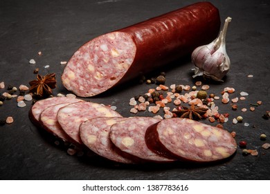 Closeup Sliced Jalapeno Cheddar Summer Sausage With Sliced Pieces Served With Pink Salt, Spices, And Whole Garlic