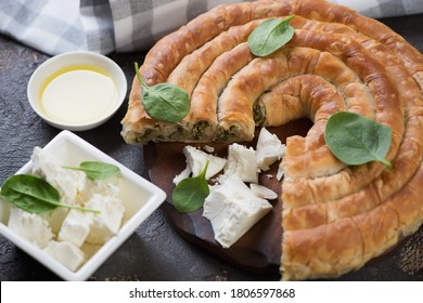 Close-up of sliced spanakopita or greek spiral pie made of filo dough, feta cheese and spinach, horizontal shot